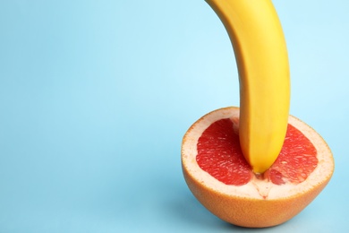 Photo of Fresh grapefruit and banana on blue background, space for text. Sex concept