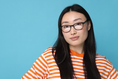 Portrait of happy woman in glasses on light blue background