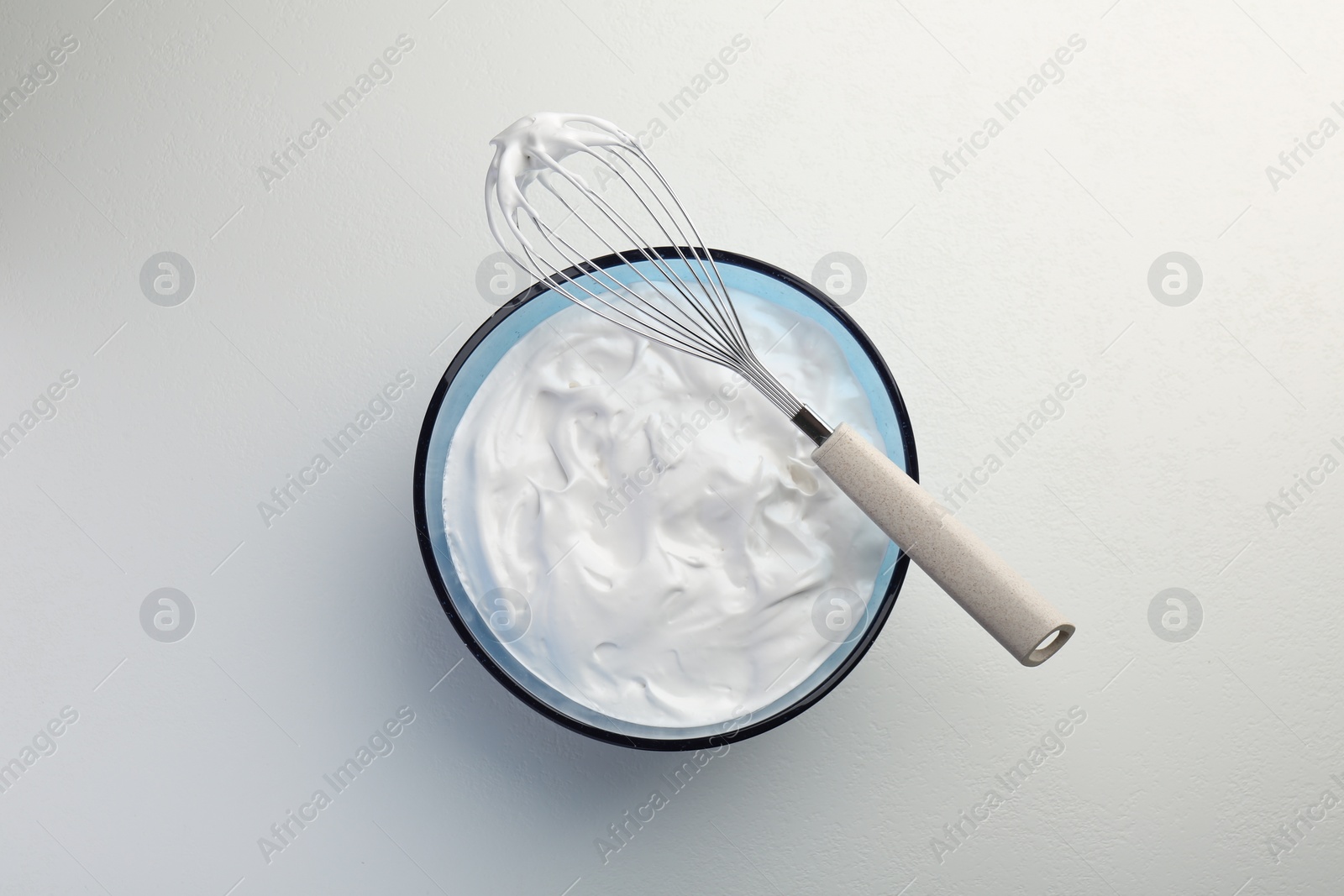 Photo of Bowl with whipped cream and whisk on light background, top view