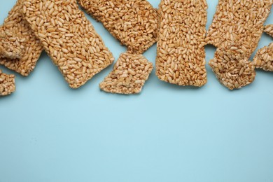 Photo of Puffed rice bars (kozinaki) on light blue background, flat lay. Space for text