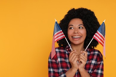 Photo of 4th of July - Independence Day of USA. Happy woman with American flags on yellow background, space for text