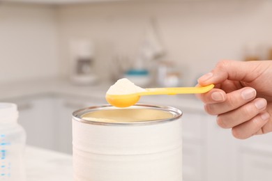 Photo of Woman with powdered infant formula indoors, closeup. Preparing baby milk