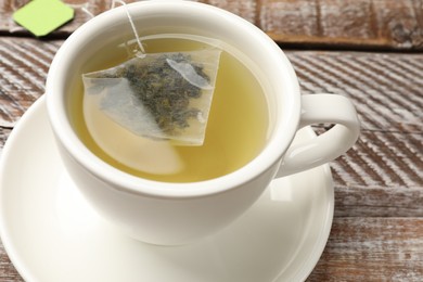 Photo of Tea bag in cup with hot drink on wooden rustic table, closeup