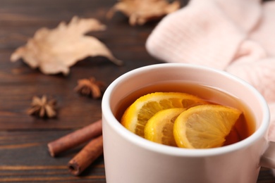 Photo of Hot tea with lemon slices on brown table, closeup