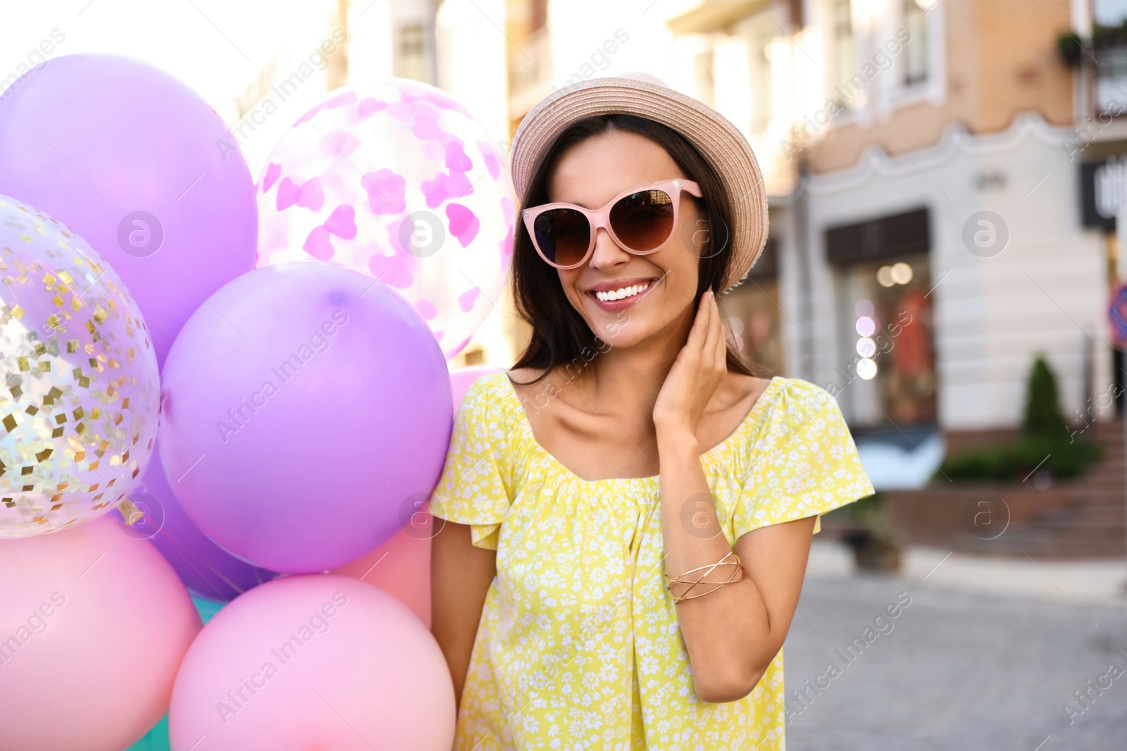 Photo of Beautiful young woman with color balloons on city street