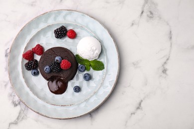 Photo of Delicious chocolate fondant served with fresh berries and ice cream on white marble table, top view. Space for text