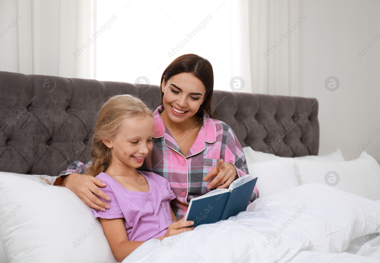 Photo of Mother and daughter reading book in bed. Help concept