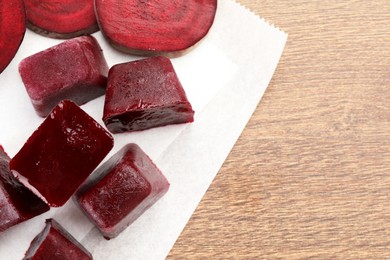 Photo of Frozen beetroot puree cube and fresh beetroot on wooden table, top view. Space for text