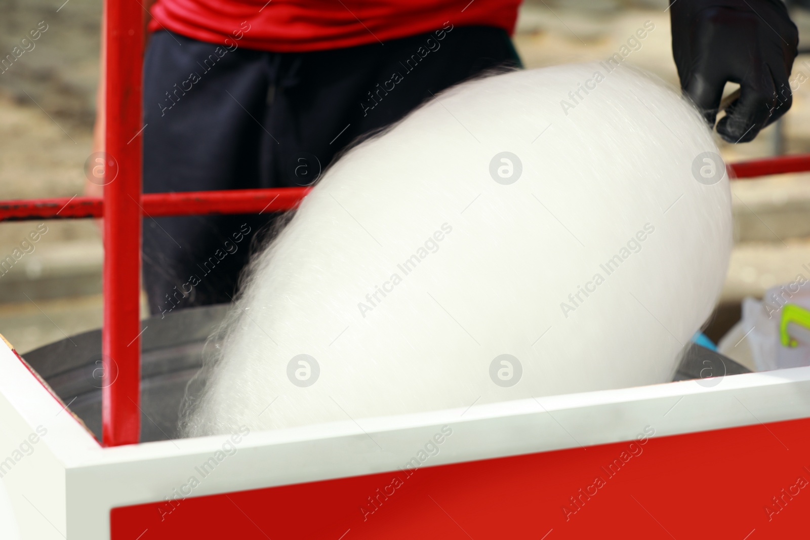 Photo of Man making cotton candy with machine outdoors, closeup