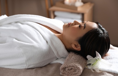 Beautiful Asian woman lying on massage table in spa salon
