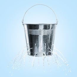 Image of Leaky bucket with water on light blue background 