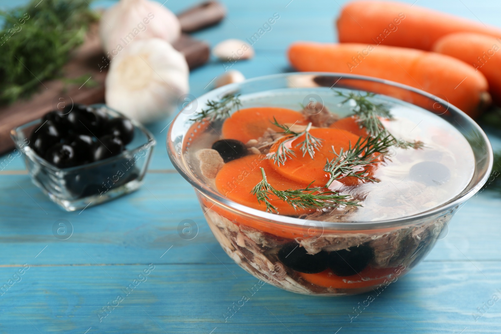 Photo of Delicious aspic with meat and vegetables served on light blue wooden table