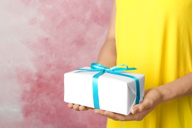 Photo of Woman holding beautifully wrapped gift box on color background