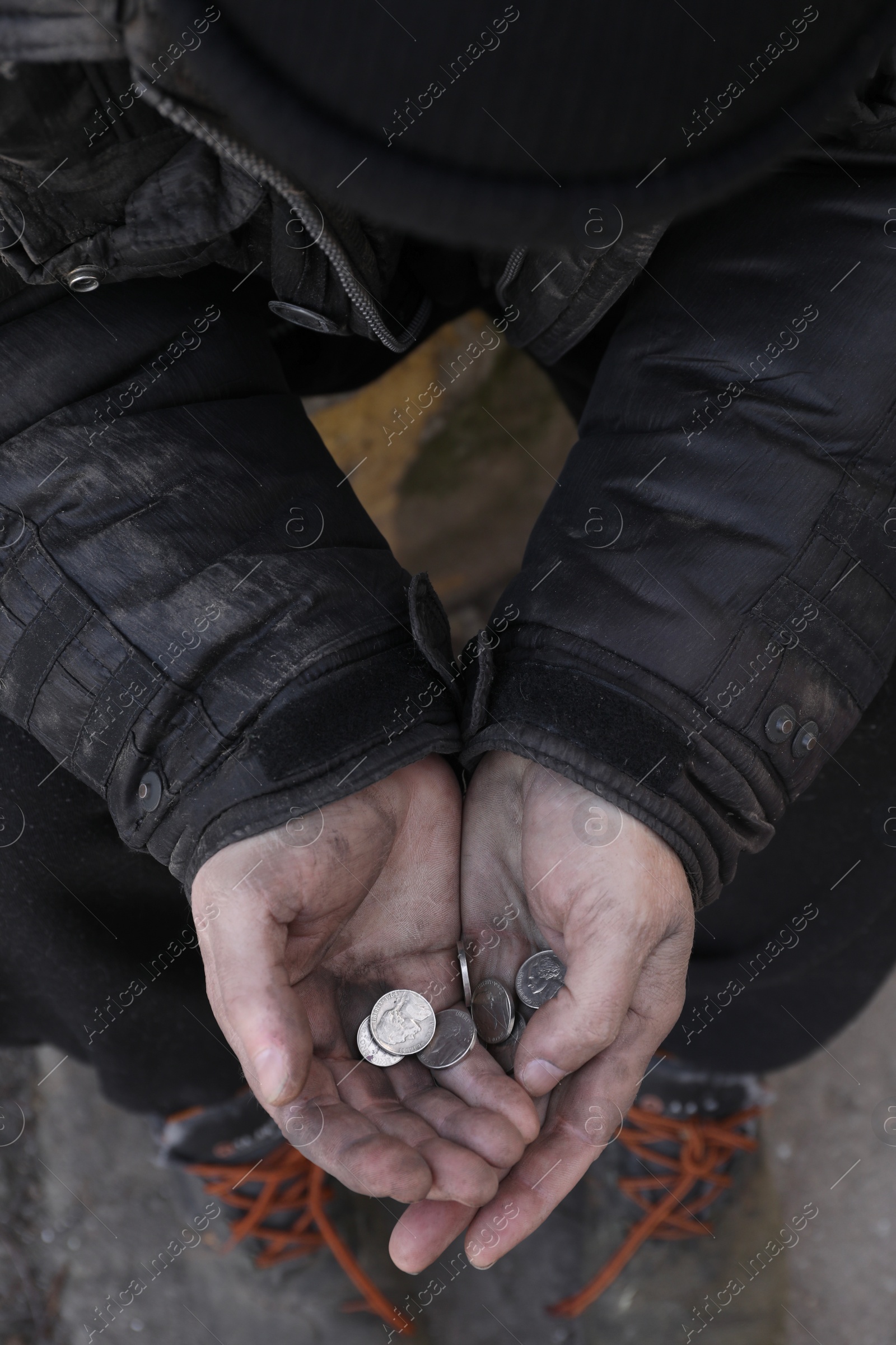 Photo of Poor homeless man holding coins outdoors, closeup