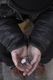 Poor homeless man holding coins outdoors, closeup