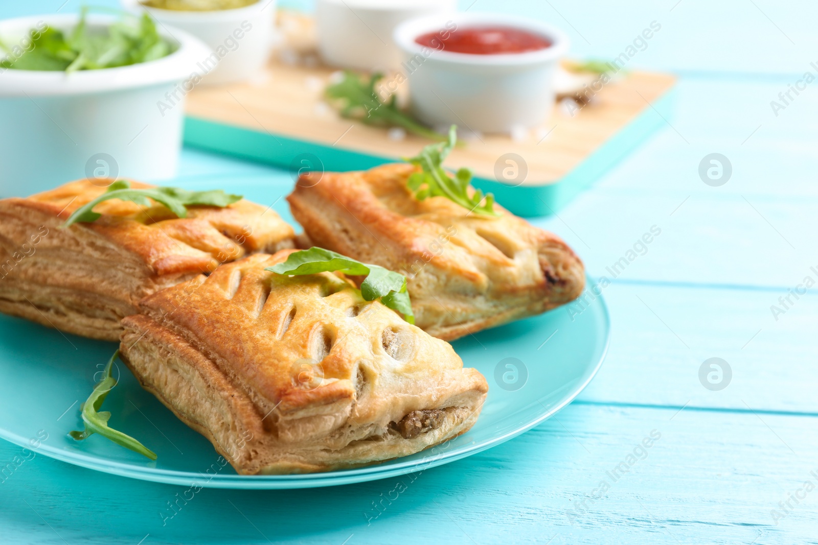 Photo of Fresh delicious puff pastry served on light blue wooden table