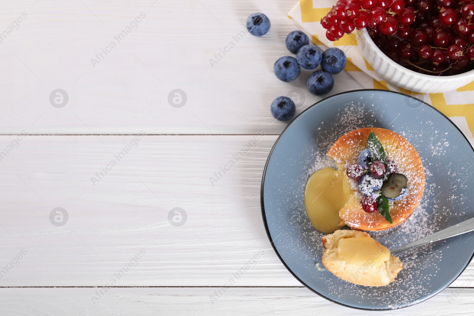 Photo of Tasty vanilla fondant with white chocolate and berries on light wooden table, flat lay. Space for text