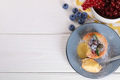 Photo of Tasty vanilla fondant with white chocolate and berries on light wooden table, flat lay. Space for text