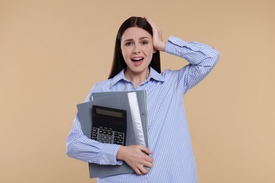Emotional accountant with calculator and folders on beige background