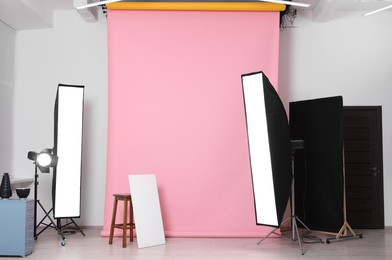 Pink photo background, stool and professional lighting equipment in studio