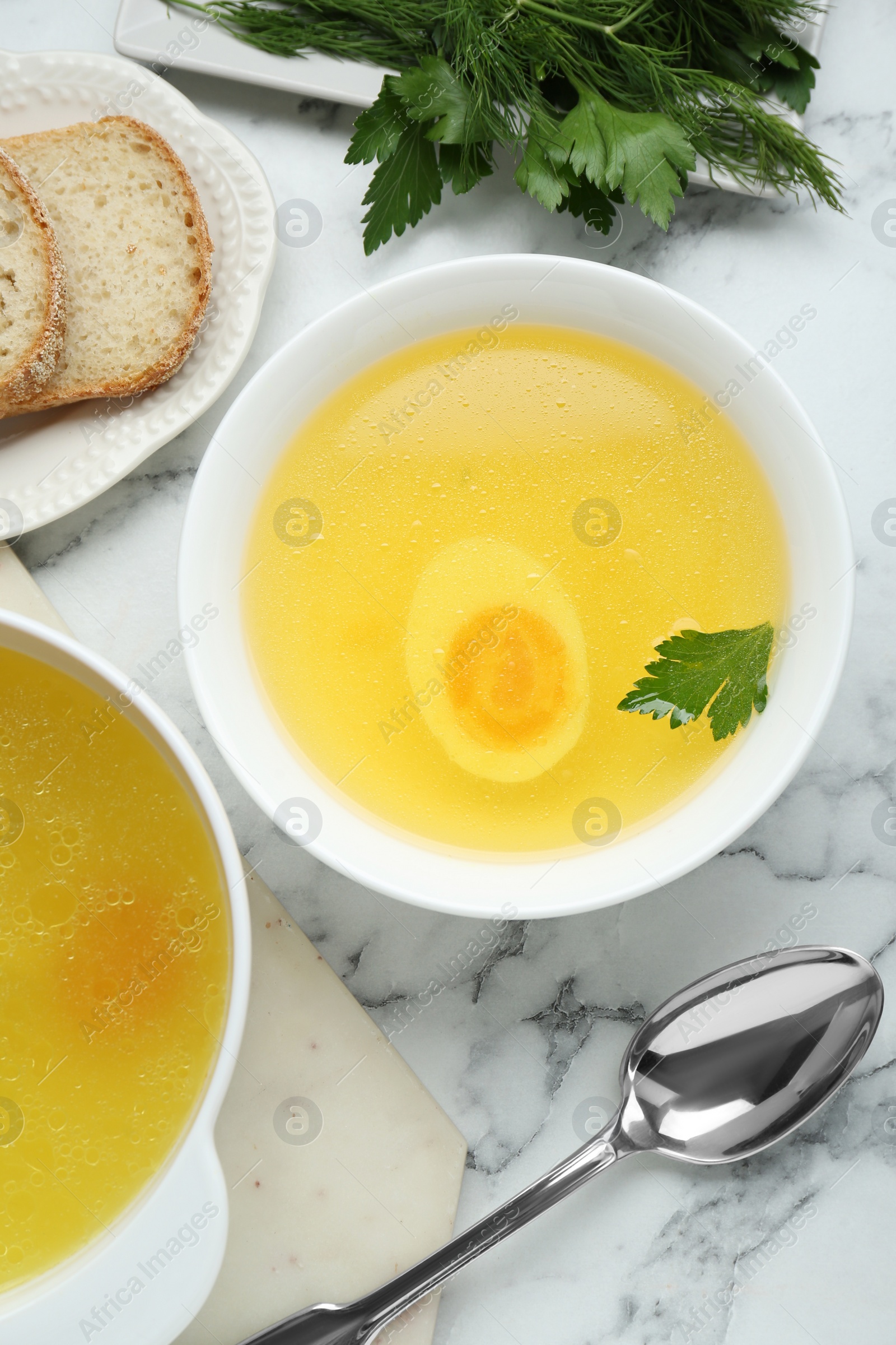 Photo of Delicious bouillon served on white marble table, flat lay