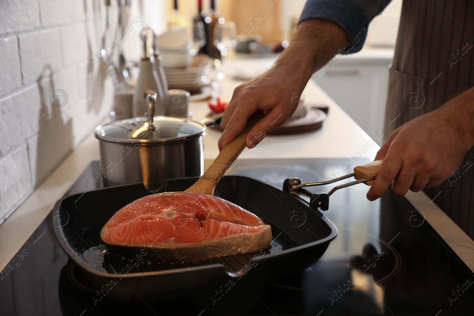 Photo of Man cooking fresh salmon steak in frying pan, closeup