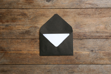 Black paper envelope on wooden background, top view