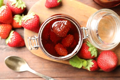 Photo of Delicious pickled strawberry jam and fresh berries on wooden table, flat lay