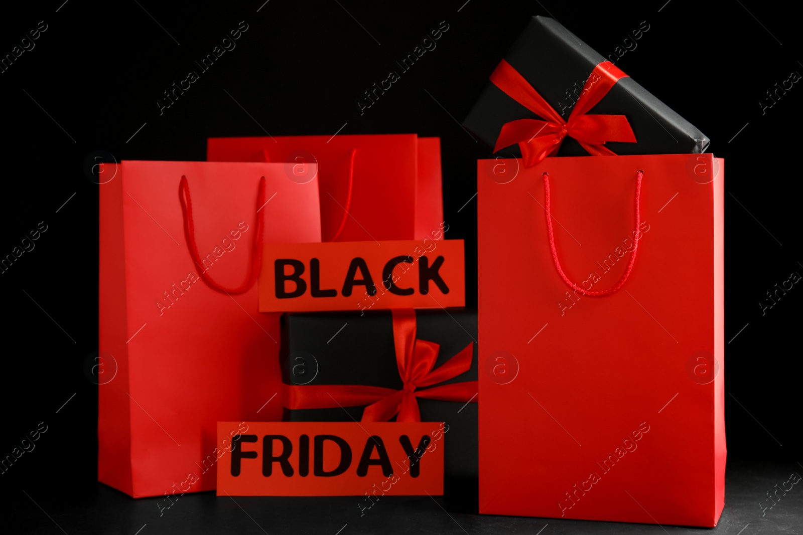 Photo of Paper shopping bags and gift boxes on dark background. Black Friday sale