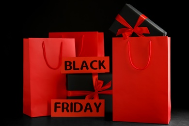 Photo of Paper shopping bags and gift boxes on dark background. Black Friday sale