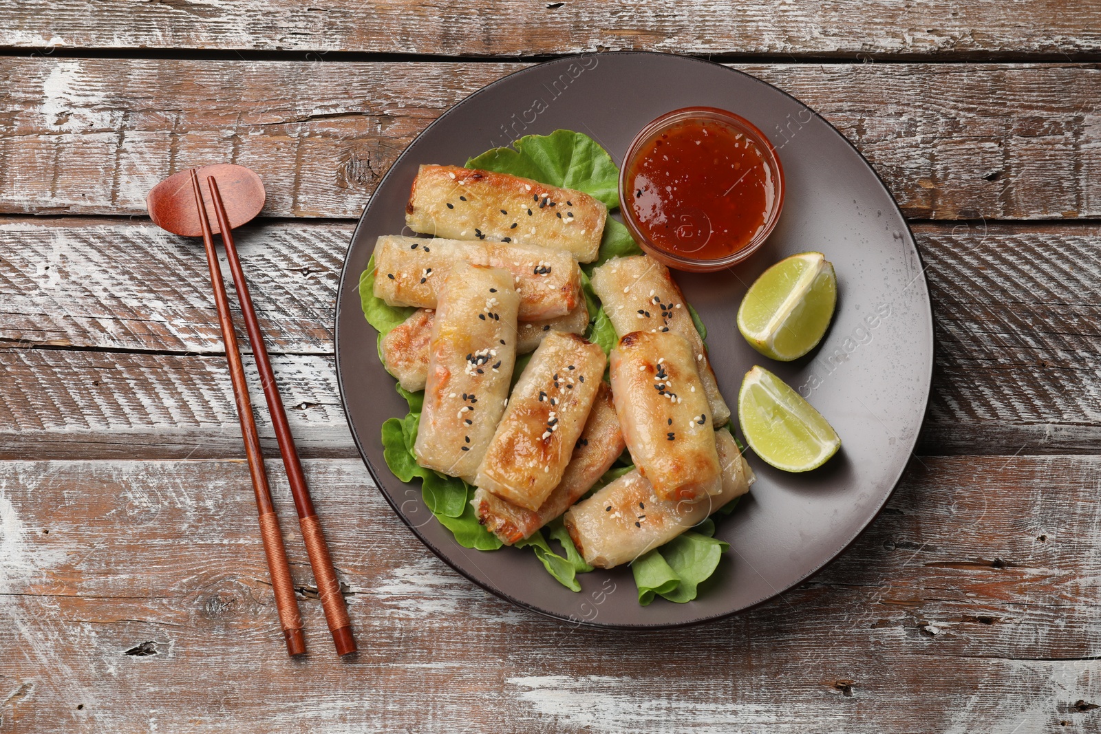 Photo of Tasty fried spring rolls served on wooden table, flat lay