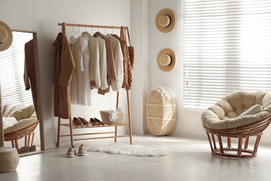 Photo of Modern dressing room interior with rack of stylish women's clothes
