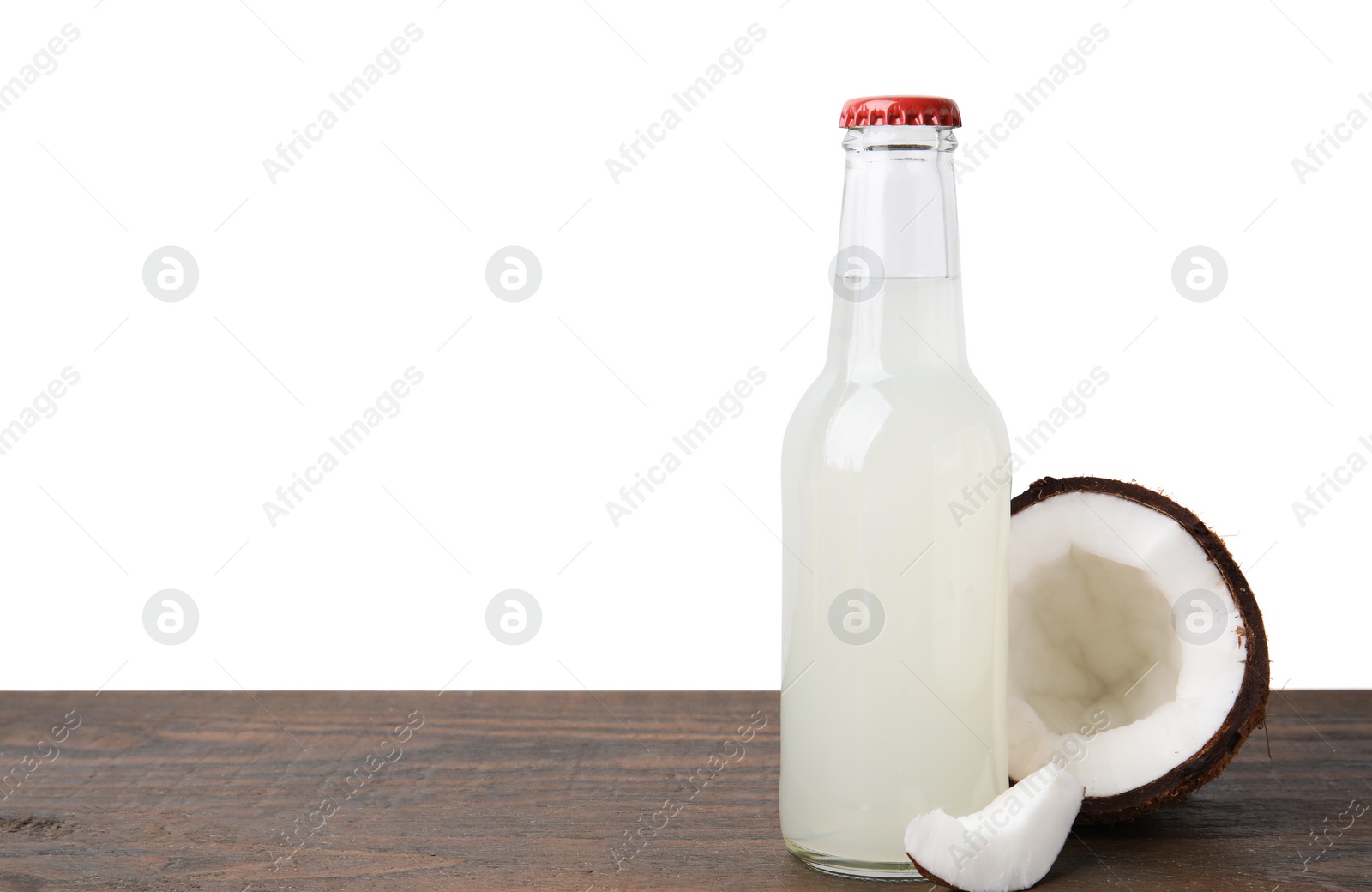 Photo of Delicious kombucha in glass bottle and coconut on wooden table against white background, space for text