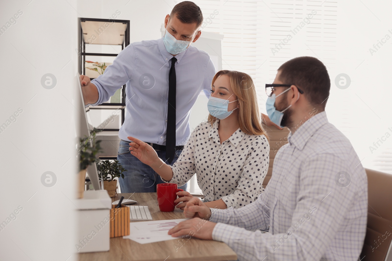 Photo of Coworkers with masks in office. Protective measure during COVID-19 pandemic