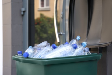 Many used plastic bottles in trash bin outdoors, closeup. Recycling problem