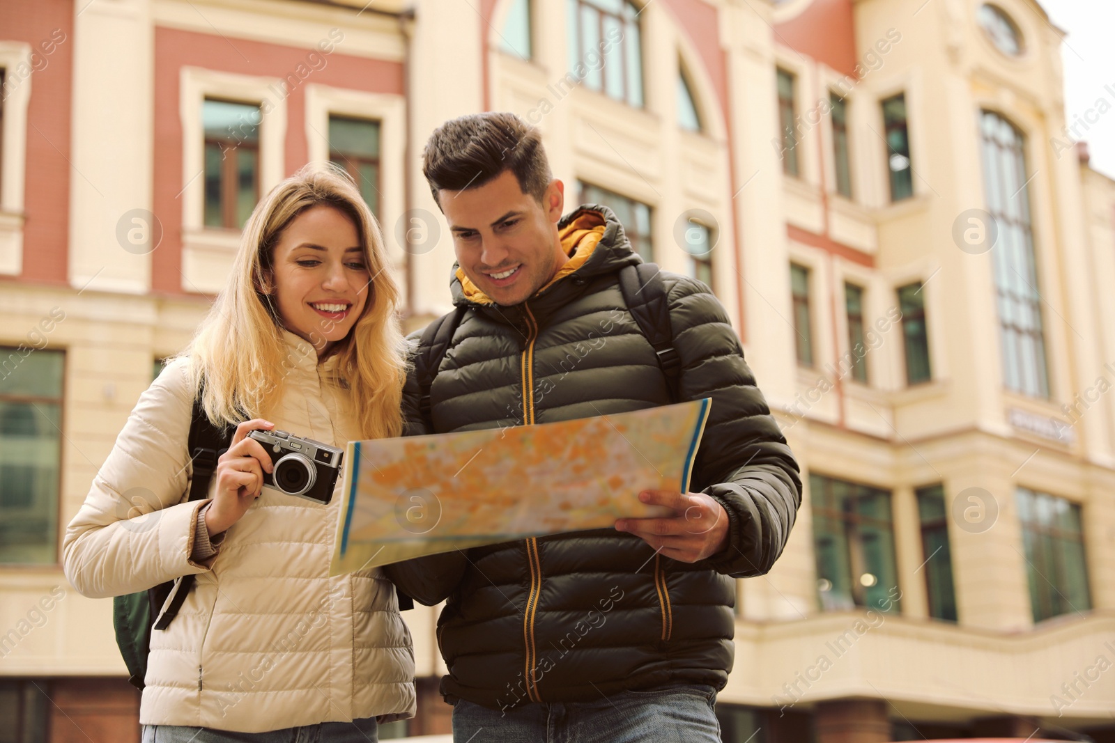 Photo of Couple of tourists with map and camera on city street