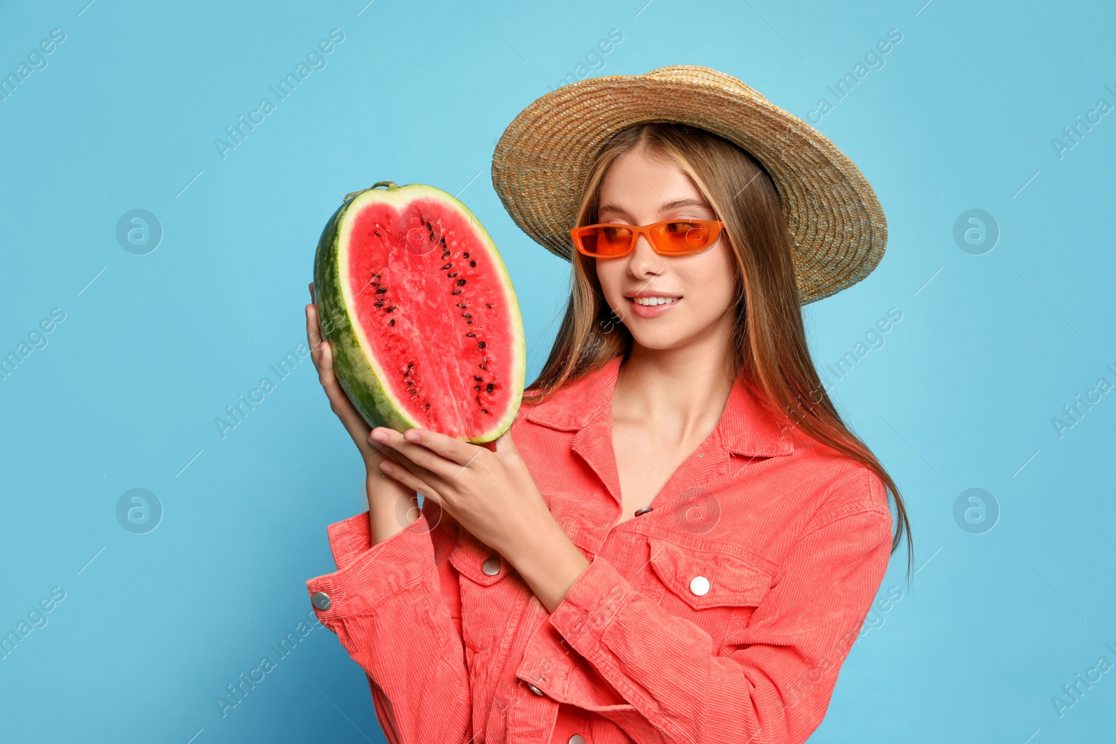 Photo of Beautiful girl with half of watermelon on light blue background