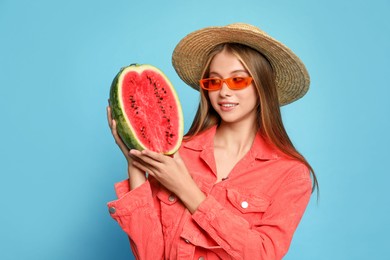 Beautiful girl with half of watermelon on light blue background