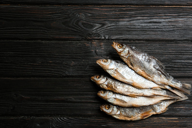 Photo of Tasty dried fish on black wooden table, flat lay. Space for text