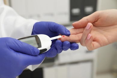 Photo of Diabetes. Doctor checking patient's blood sugar level with glucometer in clinic, closeup