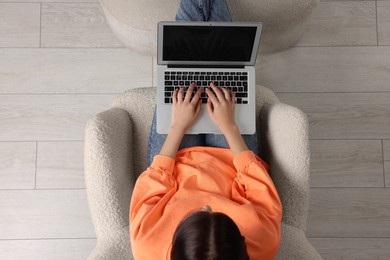 Woman working with laptop in armchair, top view