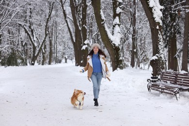 Photo of Woman with adorable Pembroke Welsh Corgi dog running in snowy park