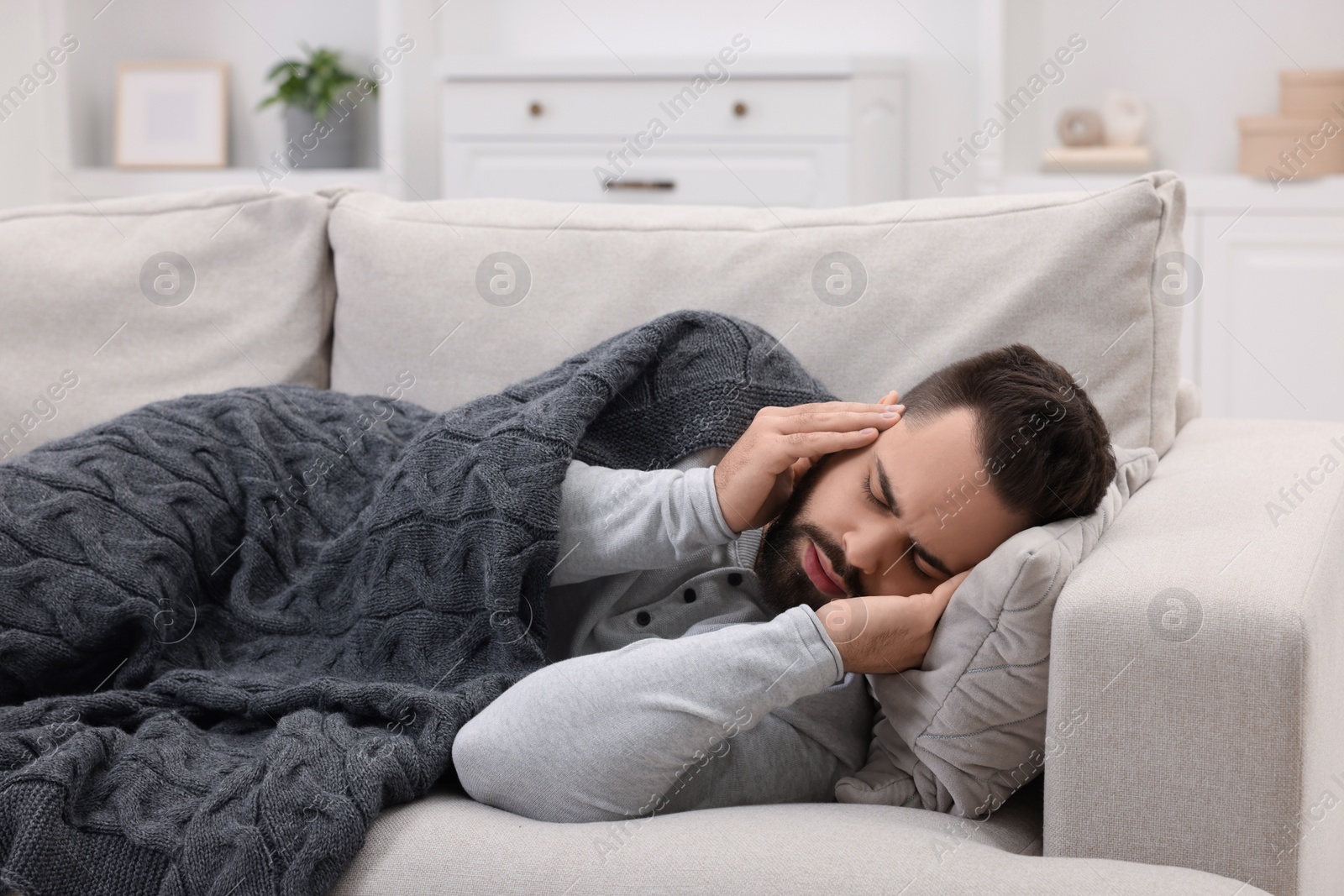 Photo of Man suffering from headache on sofa at home