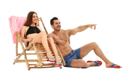 Photo of Young couple with sun lounger on white background. Beach accessories