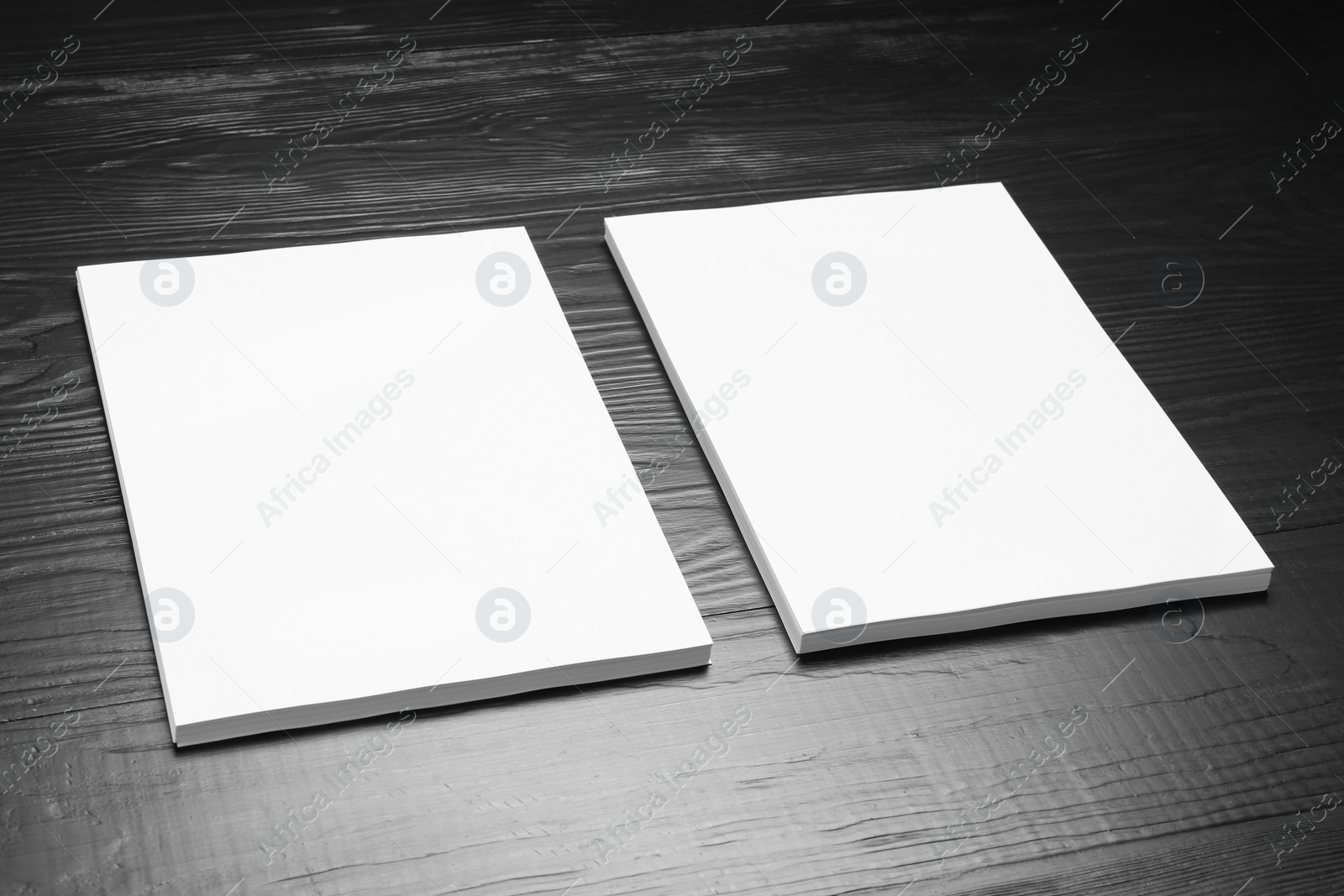 Photo of Blank paper sheets for brochure on black wooden background. Mock up