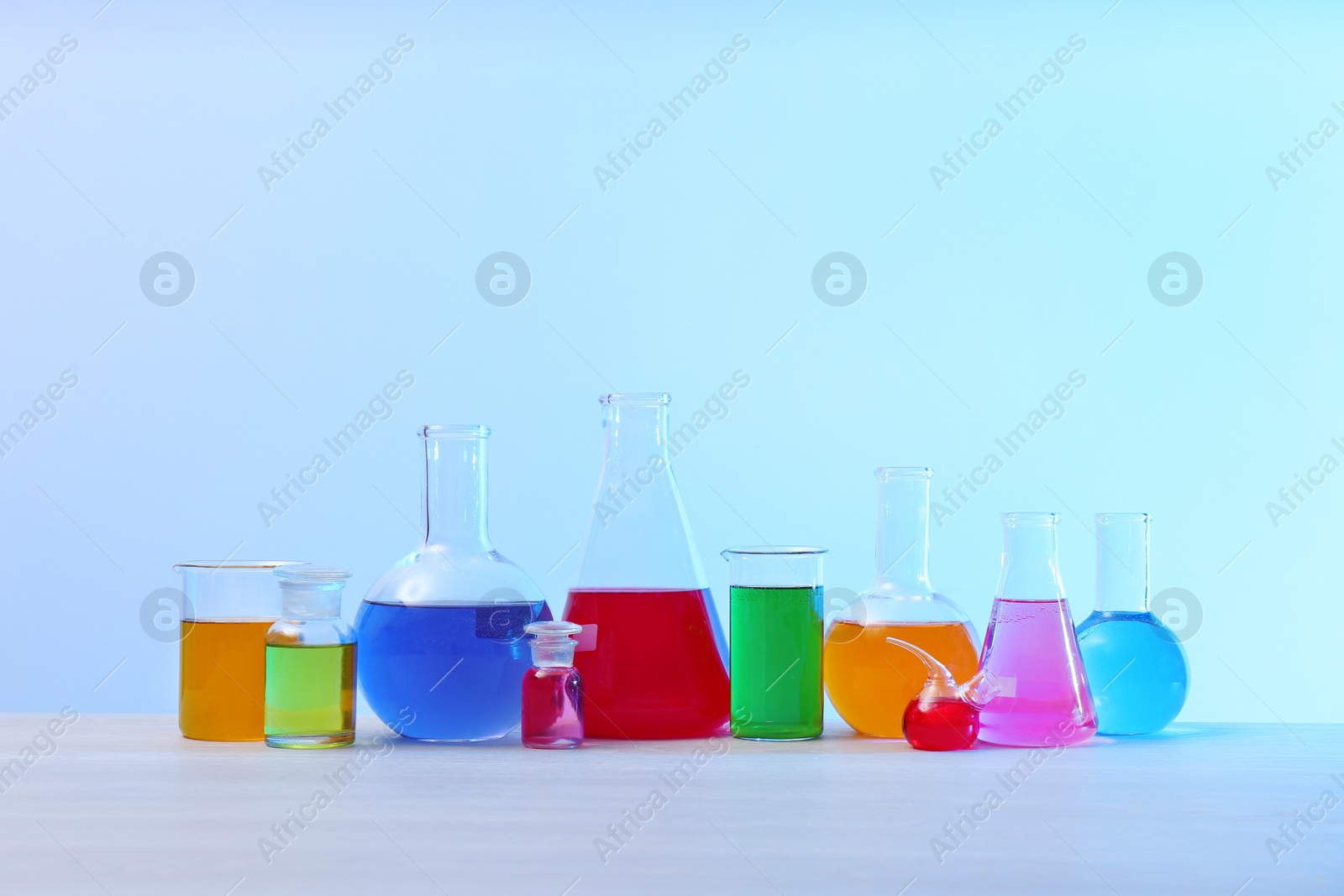 Photo of Different glassware with samples on table against light background. Solution chemistry