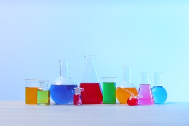 Photo of Different glassware with samples on table against light background. Solution chemistry