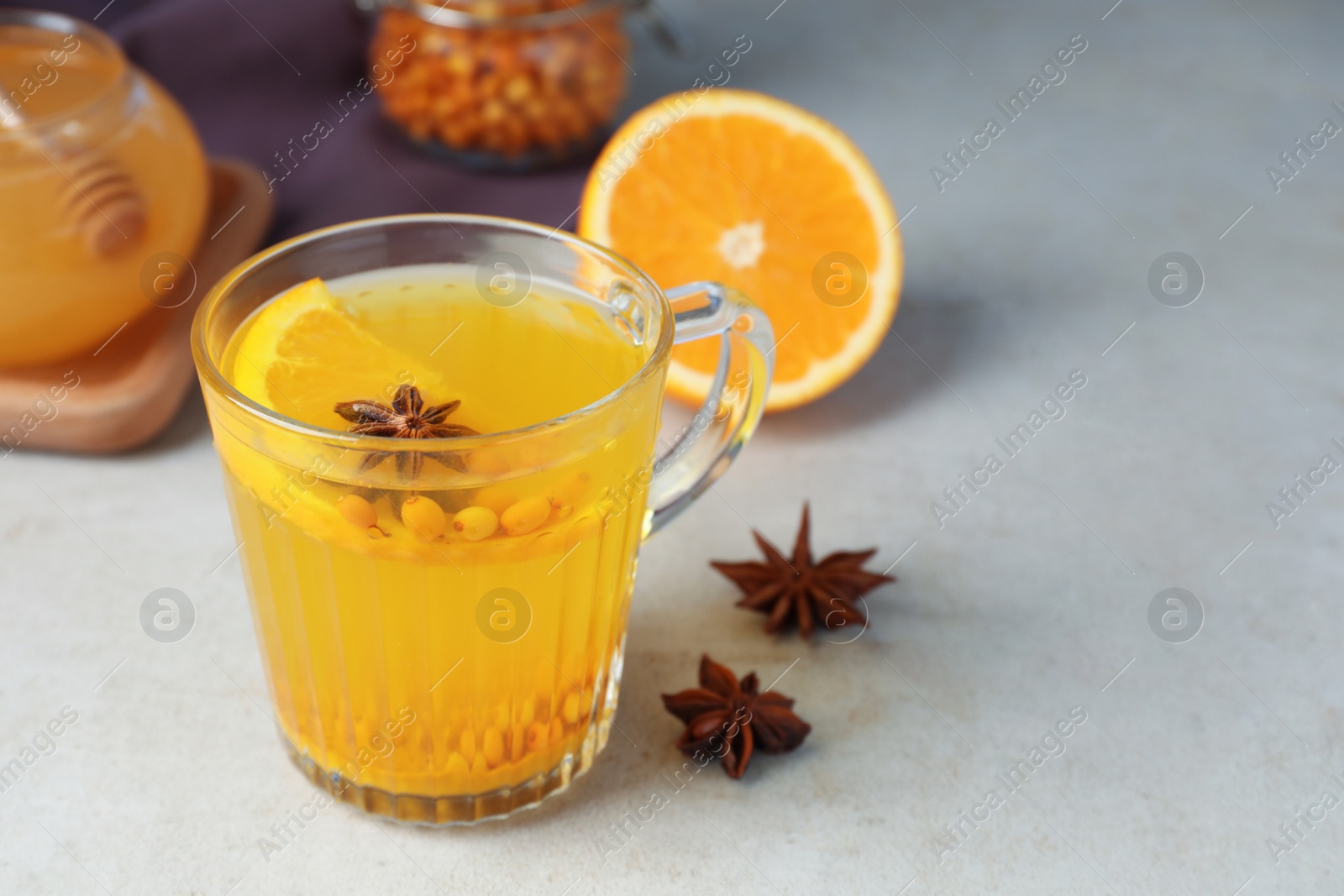 Photo of Glass cup of immunity boosting drink and ingredients on grey table, space for text