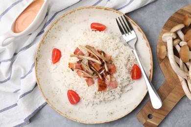 Photo of Delicious rice with bacon, mushrooms and tomatoes served on table, flat lay