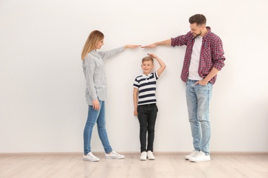 Parents measuring their son's height indoors